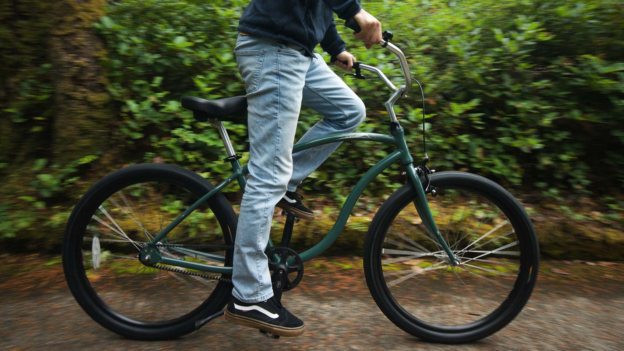 green Cypre Bikes beach cruiser being ridden on a forest path